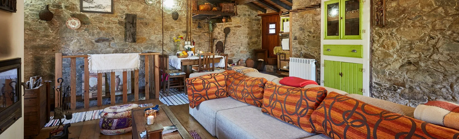 Living room with a large sofa, schist walls and a green wooden cabinet